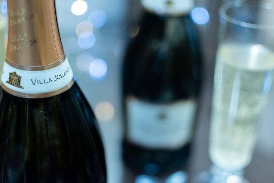 Bottle of Italian white sparkling wine Villa Jolanda Prosecco Extra Dry and flute glasses on blurred festive background with colorful lights. Ukraine, Zhytomyr, November 21, 2024