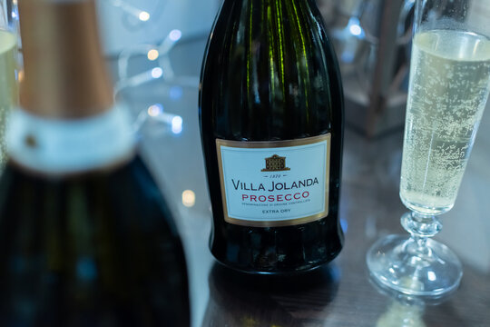 Bottle of Italian white sparkling wine Villa Jolanda Prosecco Extra Dry and flute glasses on blurred festive background with colorful lights. Ukraine, Zhytomyr, November 21, 2024