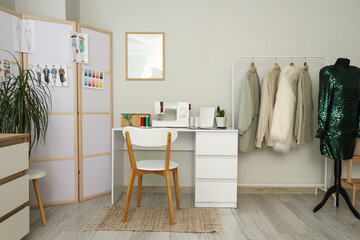 Interior of atelier with tailor's workplace, folding screen and clothes