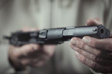 Man take care of semi automatic pistol handgun at home