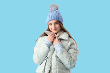 Beautiful young woman in stylish warm clothes on blue background