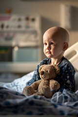 Little bald child holding a teddy bear. Small patient with oncology in a hospital. A little boy with cancer, after chemotherapy.