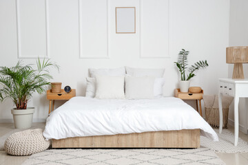 Interior of light bedroom with tables and alarm clock
