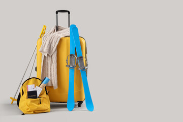 Suitcase and backpack with winter accessories on light background