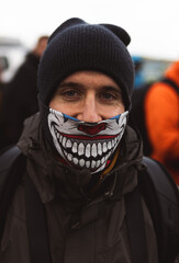 Activist in a scary clown mask and beanie joins a tense street protest, symbolizing rebellion for...