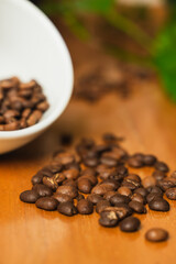 Publicity day. Colombian coffee. White cup with coffee beans sprinkled on wooden table with space for copying. Close-up.