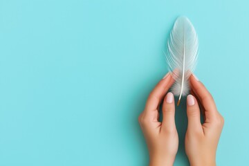 Female hands gently holding a delicate white feather on a vibrant turquoise background suggesting peace and tranquility in minimalism