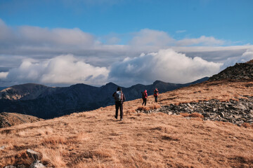 Hikers trek across a scenic mountain ridge under a dramatic, cloudy sky. Breathtaking panoramic...