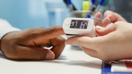 Medical specialist takes the oxygen saturation measurement and checking vital signs during a routine check up with her patient. Medic using an oximeter for accurate readings in office. Camera A.