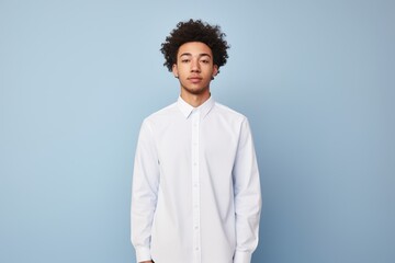 A man wearing a white shirt stands in front of a blue wall