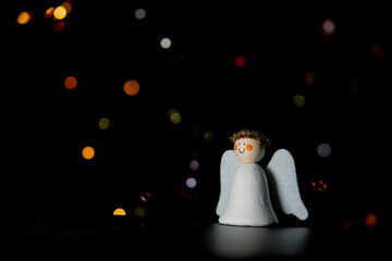 Decorative DIY Christmas Angel figure. Infront of a dark background with defocused lights in...