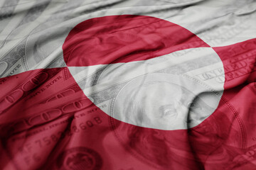 waving colorful flag of greenland on the dollar money background. finance concept. © luzitanija
