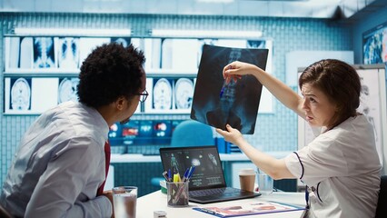 Healthcare professional sharing her medical expertise with a patient in office, reviewing x ray and...