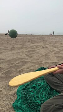 Playing with the ball and racket on the beach, a cloudy day, Argentina