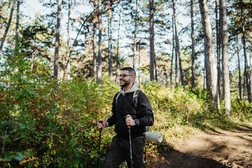 Fototapeta premium Young caucasian man hiking or trekking through the forest 