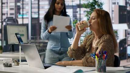 Sleepy overworked female employee yawning at her office desk, feeling exhausted with her work and suffers burnout. Businesswoman dealing with fatigue and low energy, challenges at job. Camera A.