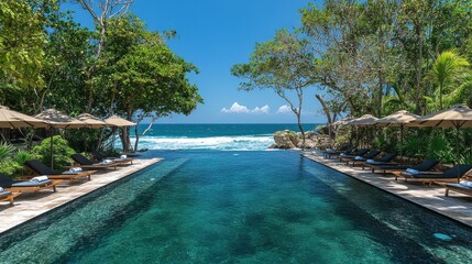 Fototapeta premium Serene Infinity Pool Overlooking Ocean Waves Surrounded by Lush Greenery and Relaxing Loungers on a Sunny Tropical Day