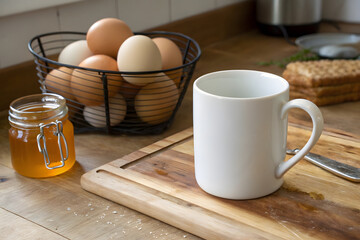 white mug sits on wooden kitchen counter beside jar of honey and basket of eggs, creating warm and inviting atmosphere for cooking