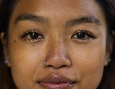 asian female teenager with nose ring smiling warmly, close-up portrait, natural beauty, at home