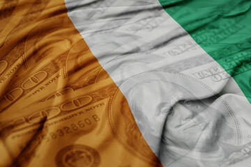 waving colorful flag of ivory coast on the dollar money background. finance concept.