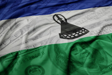 waving colorful flag of lesotho on the dollar money background. finance concept.