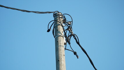 Electrical cables and telecommunication cables on iron poles. Blue sky background