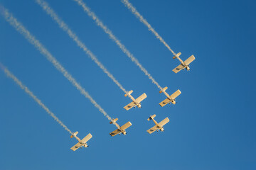 Stunt aerobatic planes performing stunts in blue sky with smoke trail. Concept of teamwork, collaboration, coordination, trust, precision, difficulty, challenge, speed, synergy