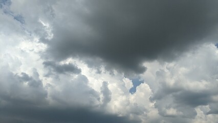 A dramatic sky with a mix of dark, stormy clouds and bright white cumulus clouds. The clouds create a sense of depth and movement.