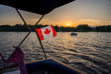 Looking at sunset on a lake with Canada flag in foreground