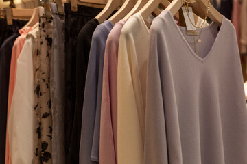 Women's jumpers on hangers in the store. Different colors and styles. Style and fashion.