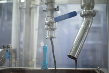 Liquid chocolate. Candy production. Chocolate flowing out of a pipe.
