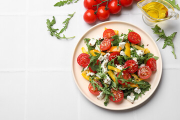 Tasty salad with arugula, cheese and vegetables on white tiled table, flat lay. Space for text