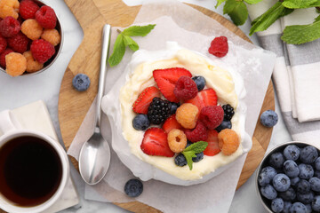 Pavlova cake (meringue dessert) with whipped cream, fresh berries and mint on table, flat lay