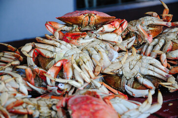 Freshly caught crabs on a wooden table at a bustling seafood market by the bay