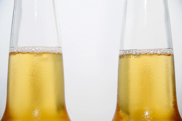 Close-up of two chilled beer bottles with condensation and golden liquid