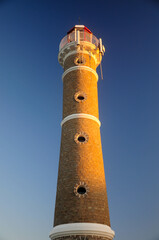 Fototapeta premium Tall lighthouse in Jose Ignacio, Uruguay at sunset against a clear blue sky