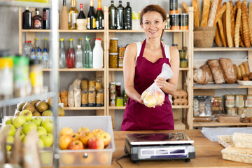 Female selling food products weighs ripe apples on scales