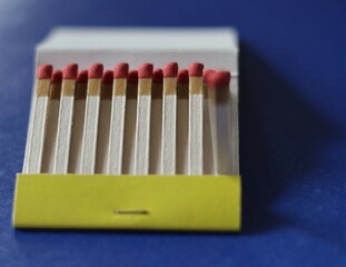Una caja con varios fósforos o cerrillas  en un fondo azul