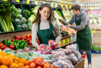 Saleswoman fills a grocery store window with ripe bell peppers