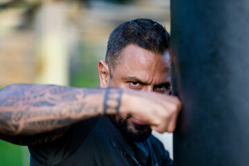 Boxer man with serious look, close up portrait. Brutal angry gang man lifestyle. Serious male sport. Strong muscular male body, muscles guy. Tattooed man boxing boxing bag. Power and sport.