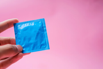 Hand Holding Condom Isolated on Pink Background With Copy Space