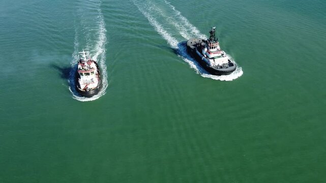 V&iacute;deo a&eacute;reo de dois pequenos navios cargueiros navegando pelo mar azul em um dia ensolarado, com ondas suaves e horizonte distante, simbolizando com&eacute;rcio mar&iacute;timo e tranquilidade