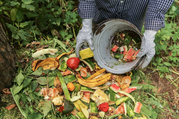 Zero waste, composting concept. Compost heap pile with bio waste. Farmer hands put weeds grass...