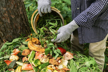 Zero waste, composting concept. Compost heap pile with bio waste. Farmer hands put weeds grass...