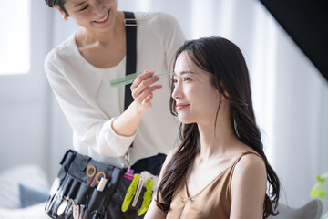 ヘアメイクの準備をするメイクさんとモデルさんの美しい横顔