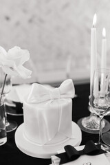 wedding cake with a bow sits on a reception table in black and white
