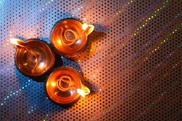 Fototapeta premium Diwali celebration. Diya lamps on color background, flat lay. Space for text