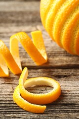 Fresh orange peels and fruit on wooden table, closeup