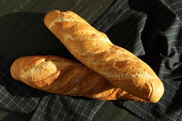 Freshly baked baguettes on black table, top view