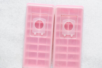 Overhead view of pink ice cube tray with a lid, top view of trendy pink ice cube trays on a white...